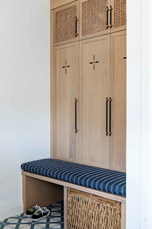 custom woodwork bench and cupboards in entryway with blue mosaic tile floor